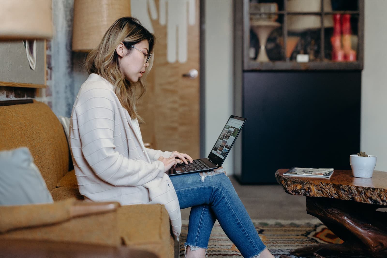 A woman sitting on a sofa with a laptop